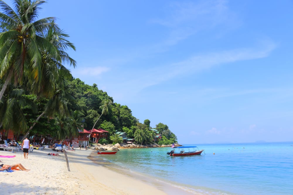 Afslappet strandliv med palmer og både ved Perhentian Islands