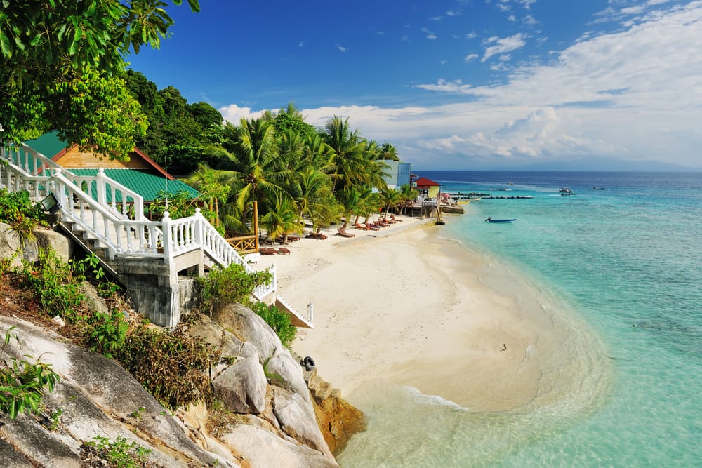 Strand og strandresort med palmer og turkis hav på Perhentian Islands i Malaysia