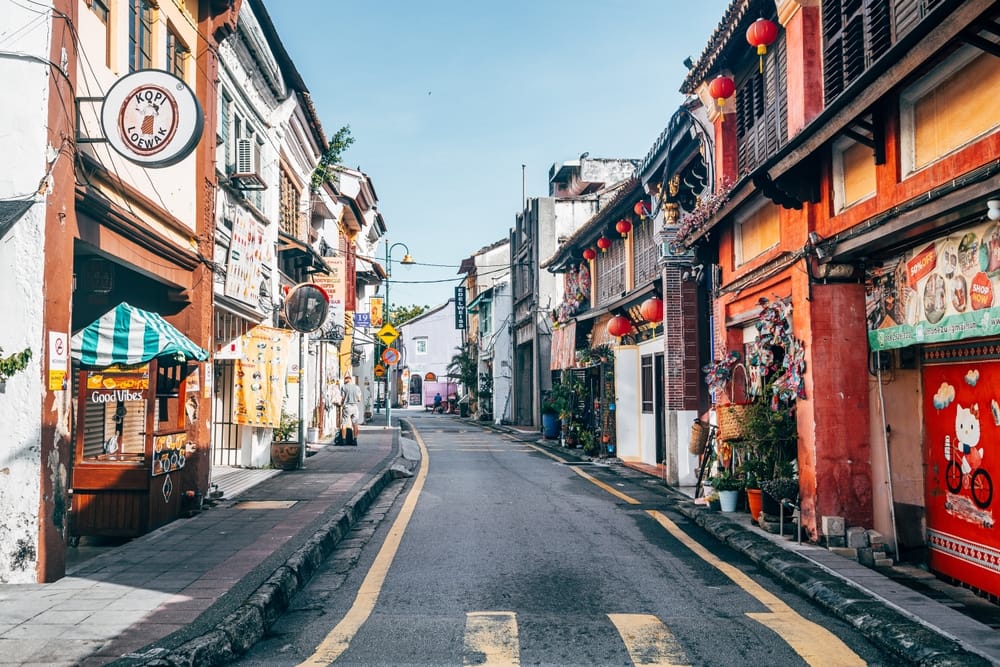Farverige shophouses og små butikker i en smal gade i George Town, Penang.
