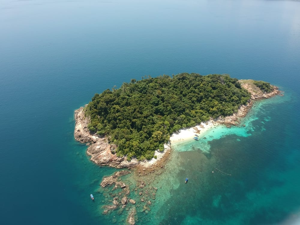 Luftfoto af grøn ø omgivet af turkis hav ved Perhentian Islands