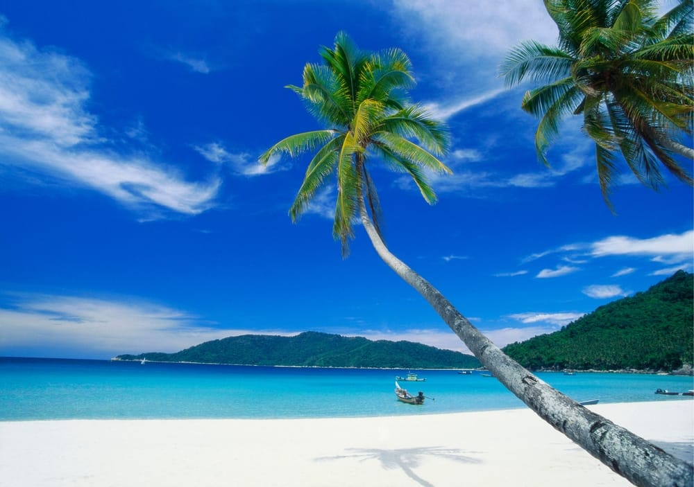 Hvid sandstrand med palmer og turkisblåt hav på Perhentian Islands i Malaysia