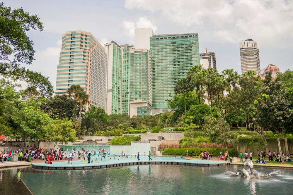 KLCC Park med springvand og mennesker foran moderne skyskrabere i Kuala Lumpur centrum.