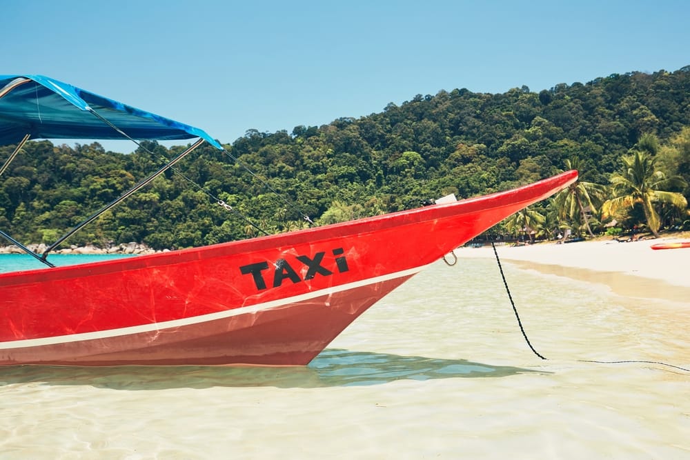 Vandtaxi ved hvid sandstrand og turkis hav på Perhentian Islands