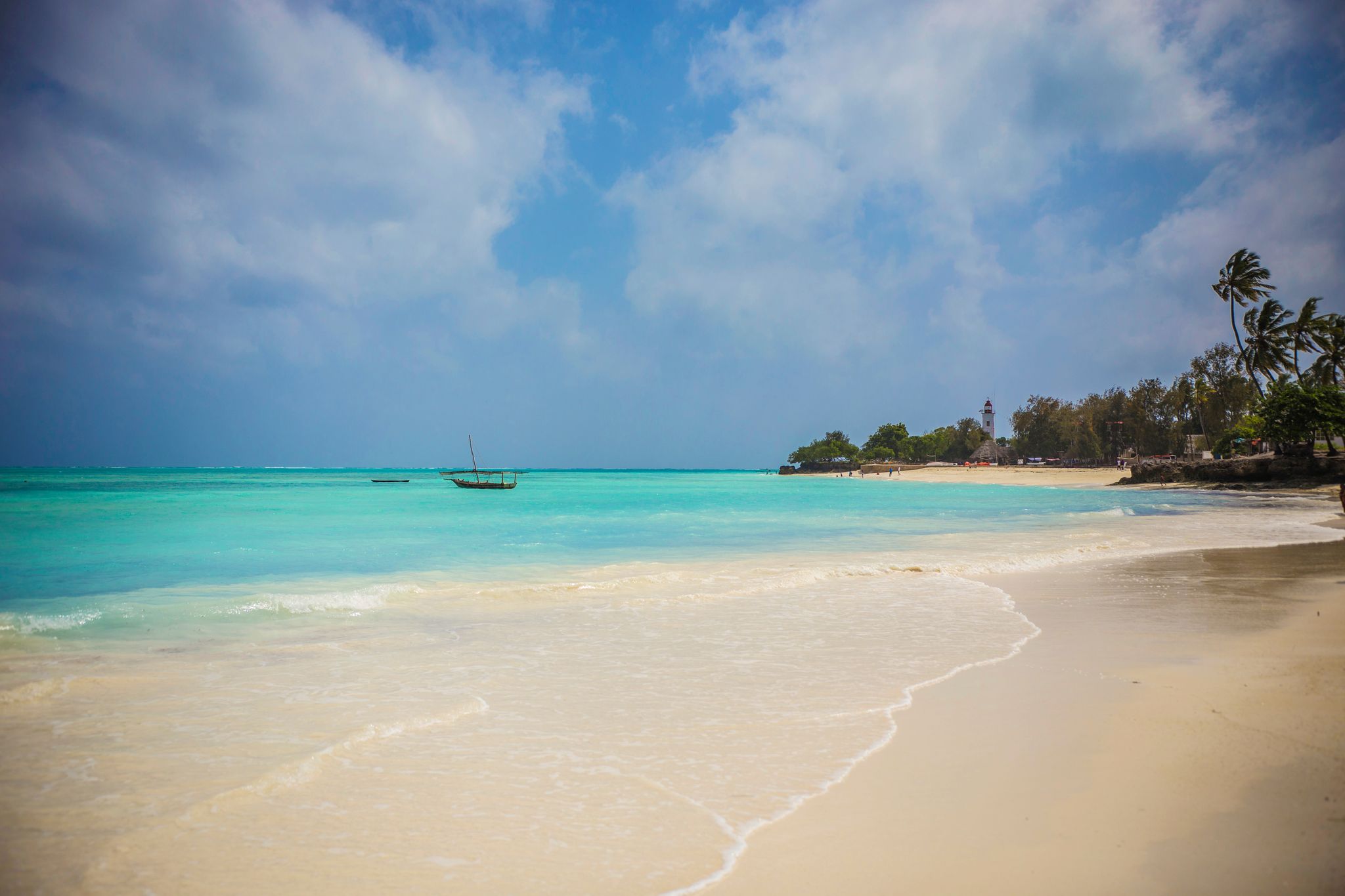 Tur­kisblåt hav, traditionel træbåd og palmer langs Nungwi Beach på Zanzibars nordkyst