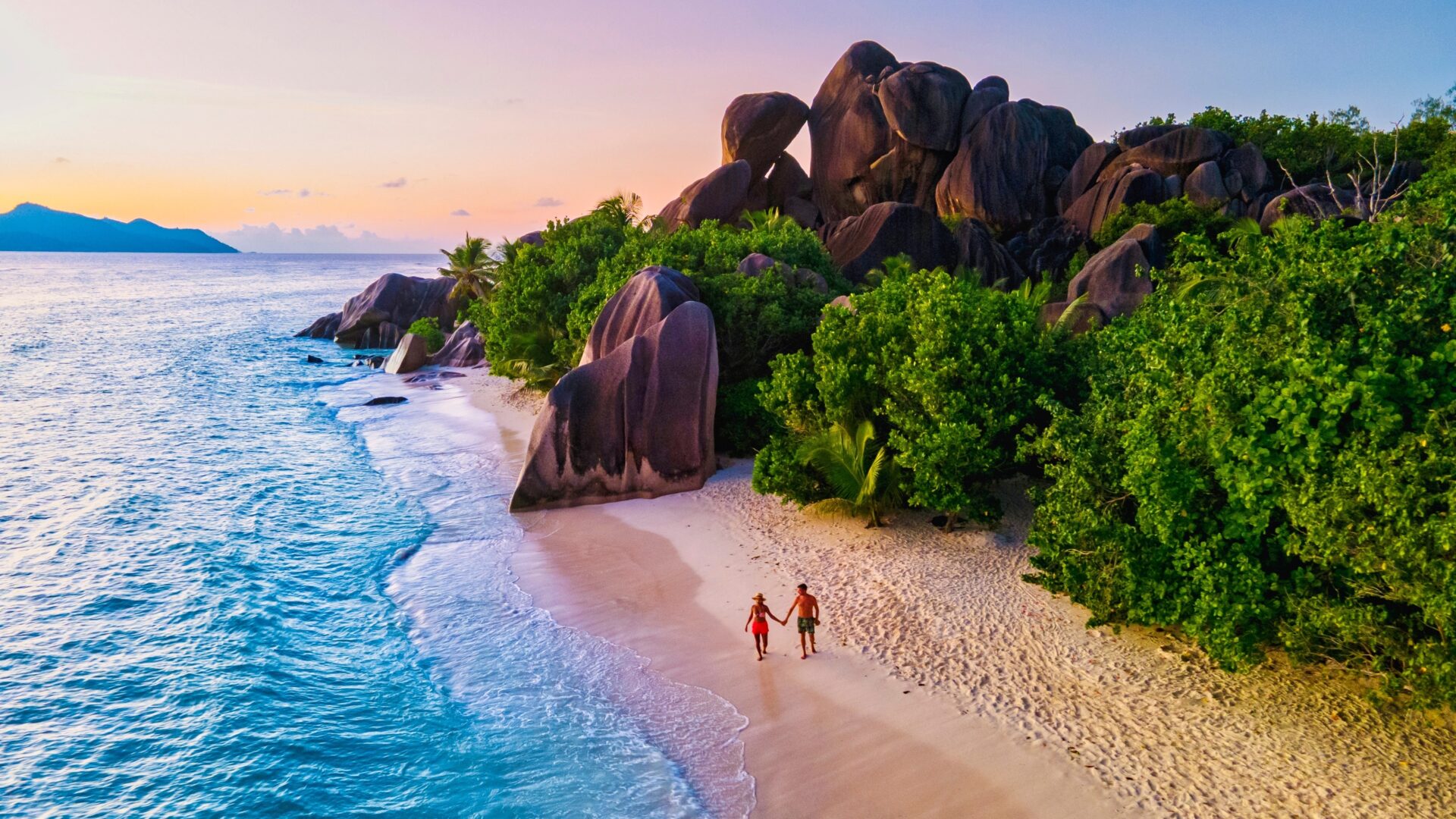 Par vandrer hånd i hånd på Anse Source d'Argent stranden på La Digue, Seychellerne