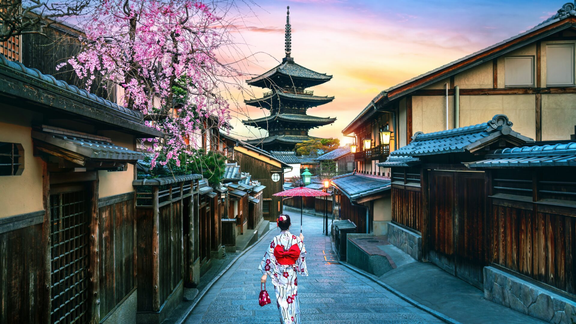 En turist iført klassisk japansk kimono står foran den ikoniske Yasaka Pagoda i Kyoto – et møde mellem kulturarv og nutid.