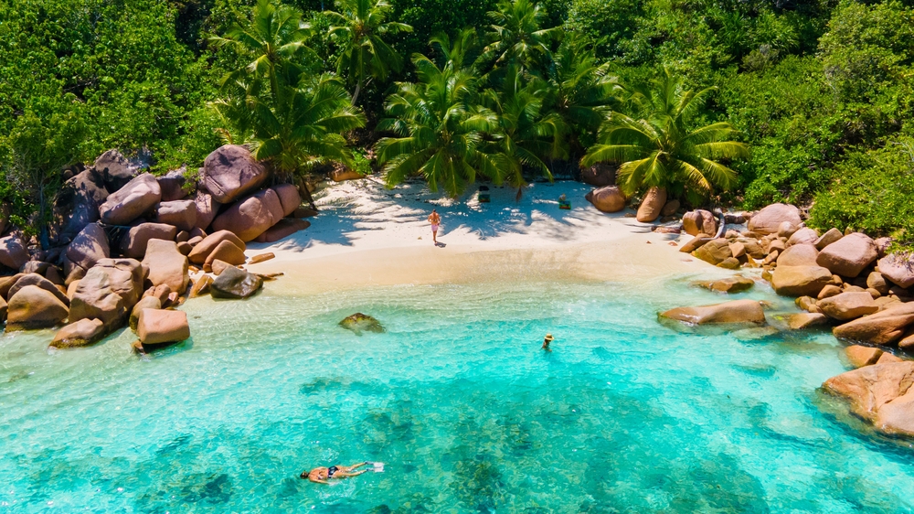 Anse Lazio på Praslin, Seychellerne – ung mandlig par nyder idyllisk strand med hvidt sand og klart turkisvand i tropiske omgivelser.