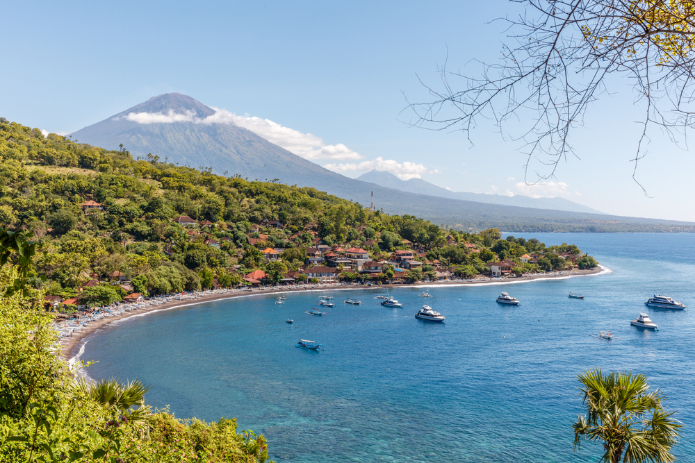 Udsigt over Agung-vulkanen fra havet – traditionelle landsbyer og huse ved kysten på Bali, Indonesien.