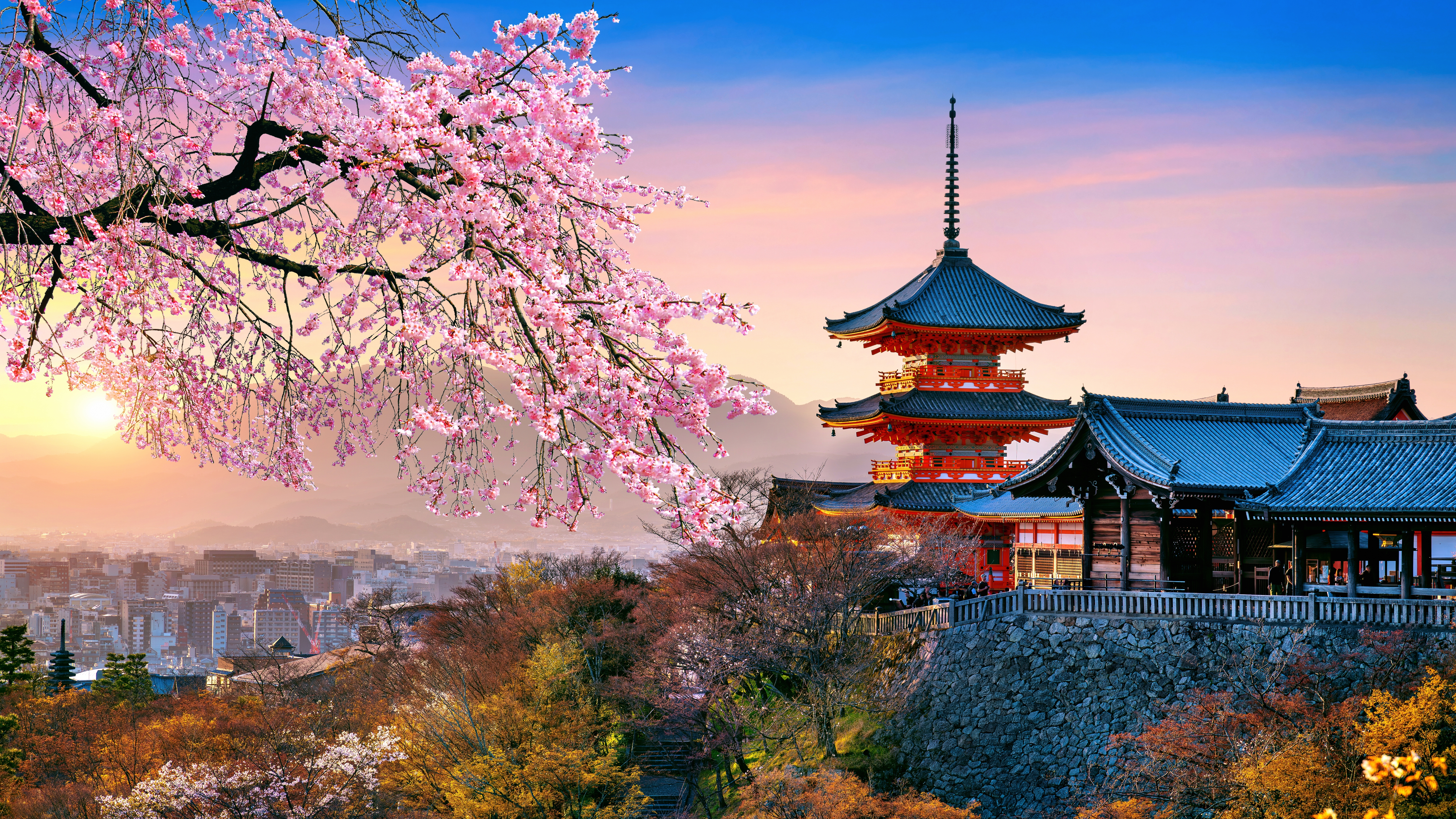 En rød pagode rejser sig blandt kirsebærblomster, badet i det gyldne lys fra solnedgangen i Japan.