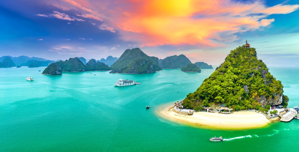 Drømmende solnedgang over Halong Bay i Vietnam – de ikoniske kalkstensøer spejler sig i havets varme nuancer.