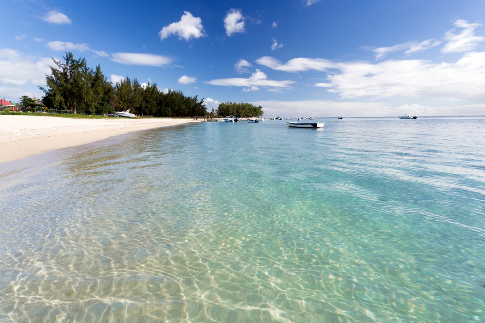 Udsigt langs Flic en Flac-stranden med klart, lavt vand.