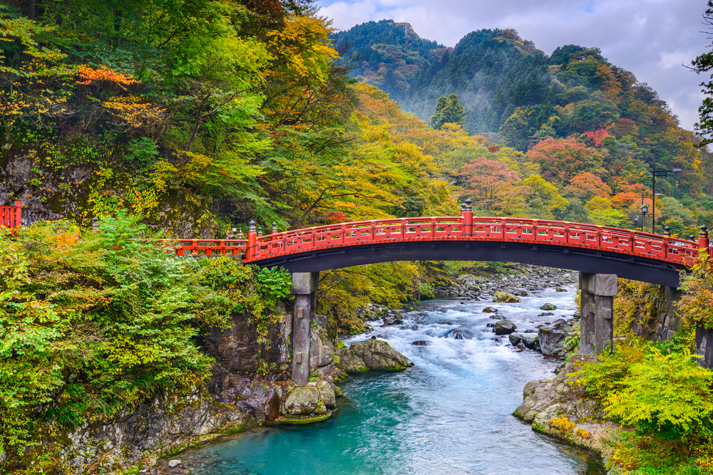 Den røde Shinkyo-bro over Daiwa-floden i Nikko, Japan, omgivet af naturskønne omgivelser og kendt som indgangen til Futarasan-helligdommen