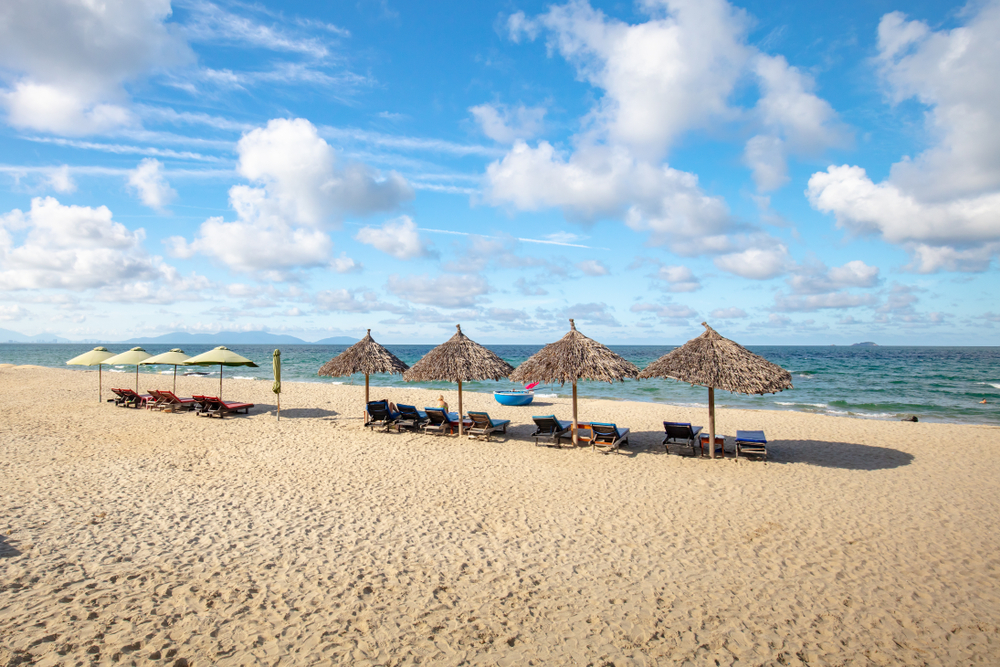 An Bang Beach nær Hoi An med gyldent sand, palmer og turister, der nyder solen ved det rolige hav.