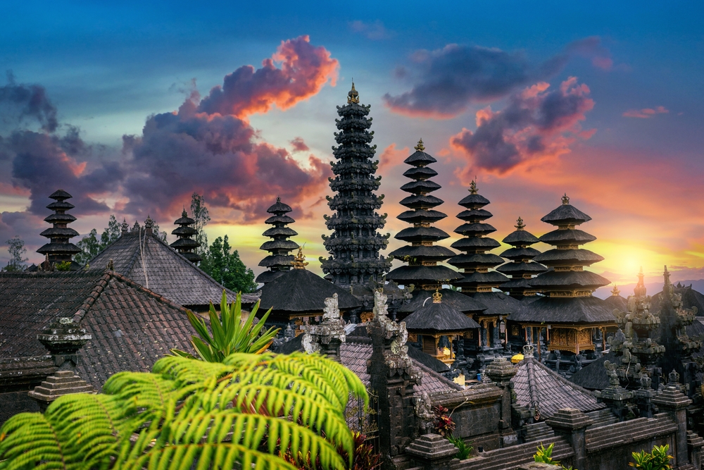 Besakih Temple i solnedgang på Østbali, Indonesien, med Gunung Agung i baggrunden og gyldent aftenlys over templerne.