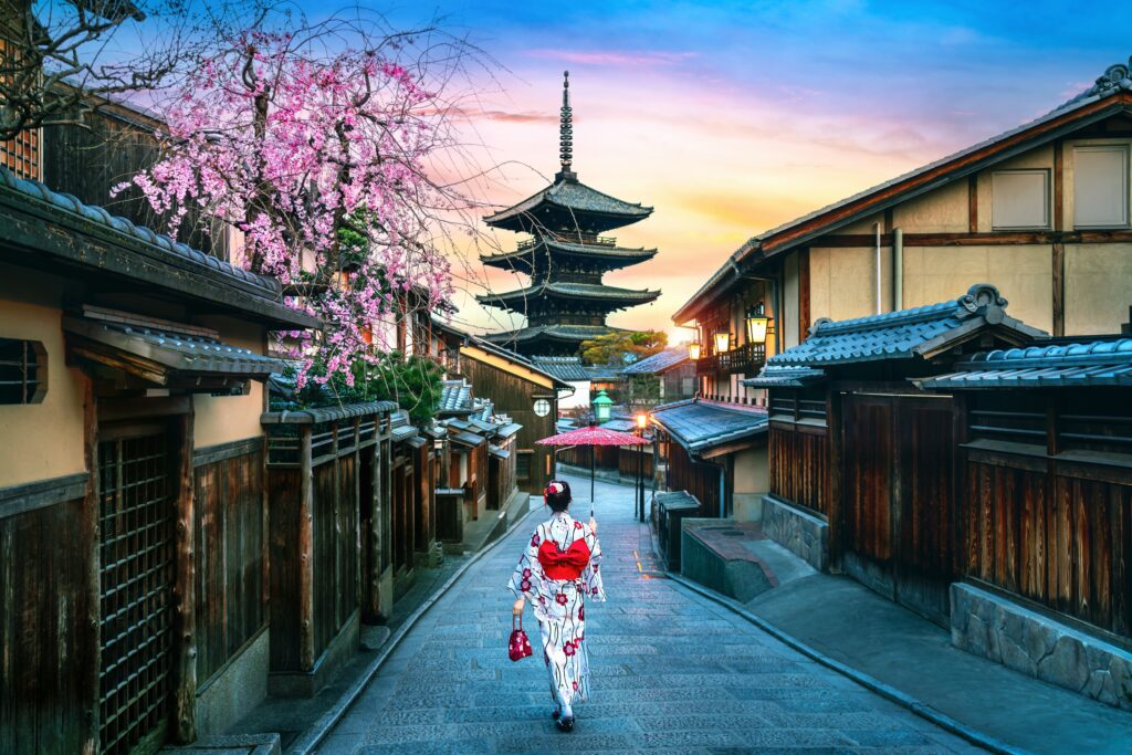 Kimono-klædt turist ved Yasaka-pagoden – ikonisk Kyoto-stemning i Higashiyama » Tembo Travel Turist i traditionel kimono foran Yasaka-pagoden i Kyoto, omgivet af historiske bygninger i Higashiyama.